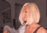 a woman with blonde hair is standing in front of a mirror in a room .