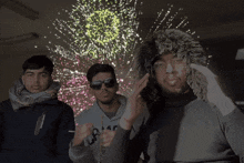 a man wearing a camper sweatshirt stands in front of a firework display