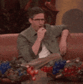 a man sitting on a couch with a bowl of berries on the table