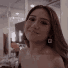 a woman in a dress is smiling and looking at the camera in a room .