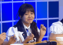 a girl is sitting at a table eating food with a fork and spoon