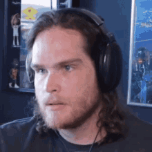 a man with long hair and a beard wearing headphones looks at the camera .