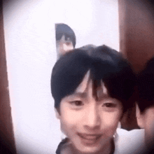 a young boy is standing in front of a door looking at the camera .