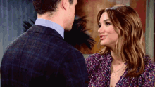 a man in a suit and a woman in a purple shirt are looking at each other