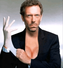 a man in a suit is holding a white glove in front of his chest