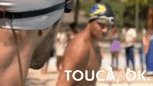 a man in a swim cap and goggles says " touca ok "