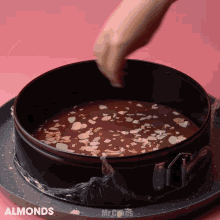 almonds are being sprinkled on top of a chocolate cake