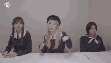 three girls are sitting at a table with the letters twice on the bottom