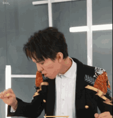a man in a black jacket and white shirt is eating food