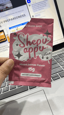 a packet of shepu appu juice is being held in front of a laptop