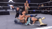 two women are wrestling in a wrestling ring with a referee