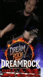 a man is playing a guitar in front of a dream rock sign