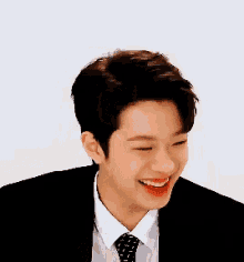 a young man wearing a suit and tie smiles for the camera
