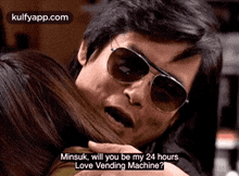 a man wearing sunglasses is hugging a woman and talking to her .