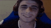 a young man wearing headphones is smiling while sitting in a blue chair .