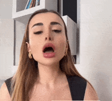 a woman is making a funny face in front of a bookshelf with a few books on it