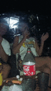 a bottle of coca cola sits on a table next to a man