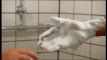 a person 's hand is covered in soap bubbles in the bathroom