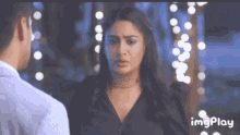 a man and a woman are standing next to each other and the woman is looking at the man .