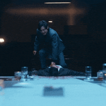 a man in a suit is standing over a man laying on the floor