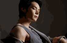 a close up of a man 's face with his eyes closed wearing a grey tank top