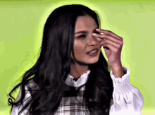 a woman with long dark hair is covering her face with her hand
