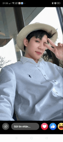 a man wearing a straw hat and a white shirt is giving a peace sign
