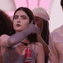 a woman wearing gloves is holding a can of soda .