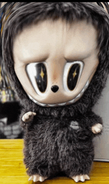 a stuffed animal with big eyes is on a wooden table