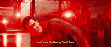a man in a superman suit is laying on the floor and says you 're not the man of steel i am