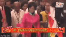 a woman in a pink top stands in a crowd