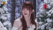 a girl with red hair is smiling in front of a christmas tree ..