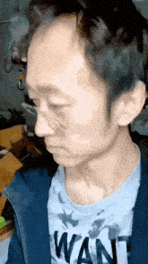 a close up of a man 's face with a wan shirt on