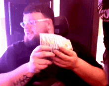 a man with a tattoo on his arm holds a pile of money