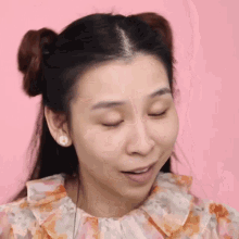 a woman with two buns in her hair is making a funny face .