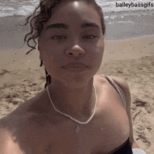a woman taking a selfie on the beach with baileybassgifs in the corner