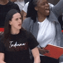 a woman wearing an indiana t-shirt holds a notebook