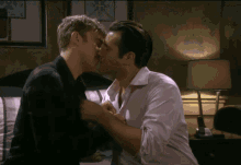 two men are kissing in front of a lamp