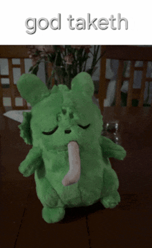 a green stuffed animal with a tongue sticking out and the words god taketh written on the bottom