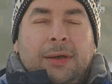 a man wearing a hat and a jacket with his eyes closed .