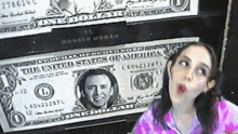 a woman stands in front of a one dollar bill with a picture of barack obama on it