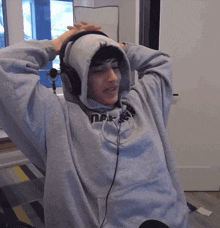 a person wearing headphones and a grey hoodie that says ' nsf ' on it