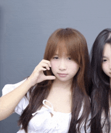 a girl with long brown hair is standing next to another girl with dark hair