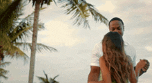 a man and a woman are dancing in front of a palm tree