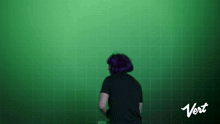 a woman with purple hair is standing in front of a green wall with the word vert on the bottom