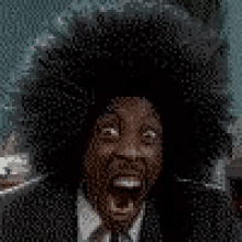 a man in a suit and tie with a large afro is making a funny face .
