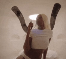 a woman in a white crop top and white underwear holds a bottle