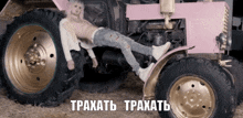 a man laying on top of a pink tractor with the words traxatb traxatb written on the bottom