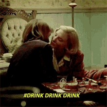 a woman kissing another woman with #drink drink drink written in the corner
