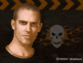 a man with a chain around his neck is standing in front of a skull and flames